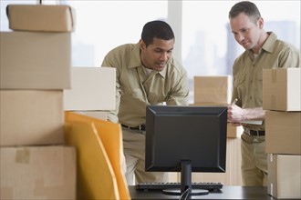 Multi-ethnic delivery men looking at computer.