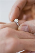 Man putting engagement ring on woman’s finger.