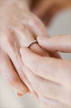 Man putting wedding ring on woman’s finger.