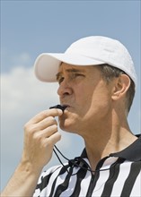 Male referee blowing whistle.