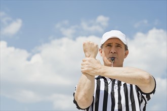Male football referee making holding call.