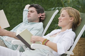 Couple reading in lounge chairs.
