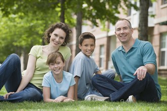 Family with two children sitting on grass.