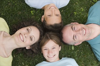 Family with two children laying on grass.