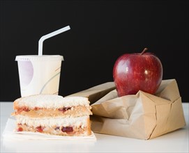 Sandwich, apple and drink next to paper bag. Date : 2008