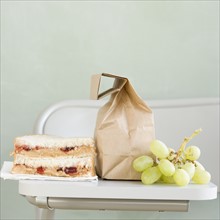 Sandwich and grapes next to paper bag. Date : 2008
