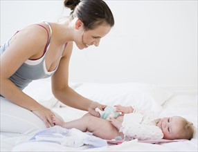 Mother changing baby’s diaper. Date : 2008