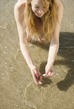 Woman picking up seashells at beach. Date : 2008