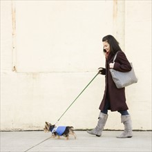 Woman walking dog on sidewalk. Date : 2008
