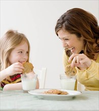 Mother and daughter dunking cookies in milk. Date : 2008