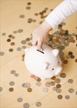 Child putting coin in piggy bank. Date : 2008