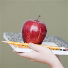Child holding apple and pencil on notebook. Date : 2008