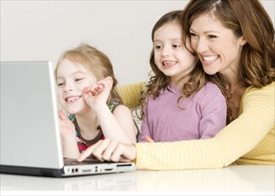 Mother and daughters looking at laptop. Date : 2008