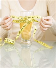 Woman tying measuring tape around glass of beer. Date : 2008
