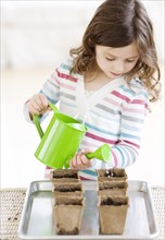 Girl watering small potted plants. Date : 2008