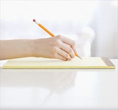 Woman writing on notepad. Date : 2008