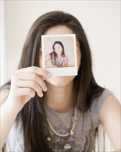 Woman holding photograph in front of face. Date : 2008