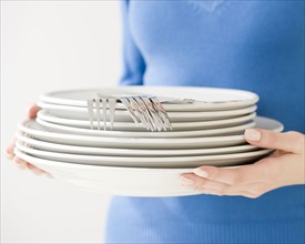 Woman holding stack of dishes. Date : 2008
