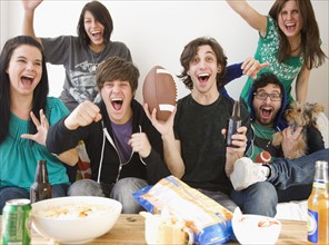 Group of friends cheering on sofa. Date : 2008