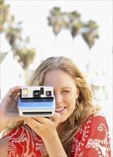 Woman taking photograph with instant camera. Date : 2008