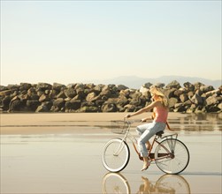 Woman riding bicycle on beach. Date : 2008