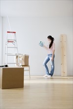 Woman holding paint swatches up to wall. Date : 2008