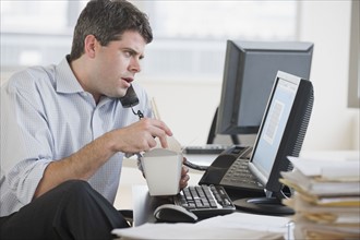 Businessman eating take out food at desk.