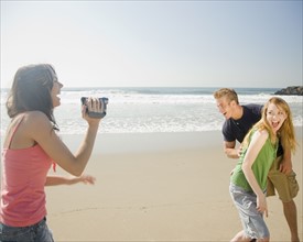Woman video recording friends at beach. Date : 2008
