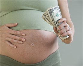 Pregnant woman holding money.