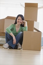 Woman leaning on moving box in new house.