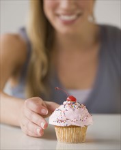 Woman reaching for cupcake.