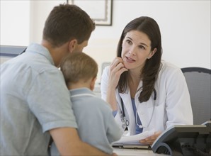Female doctor talking to father and son.