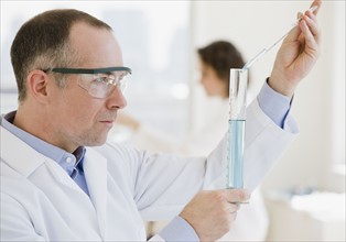 Male scientist measuring liquid in vial.