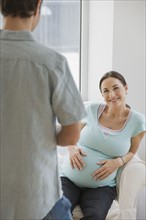Pregnant Hispanic woman smiling at husband.