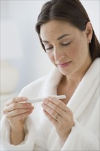 Hispanic woman looking at pregnancy test.
