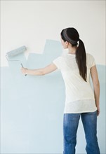 Woman painting wall with paint roller.