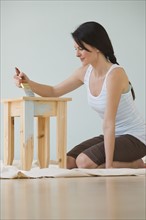 Woman painting wooden table.
