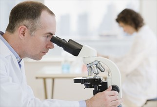 Male scientist looking into microscope.