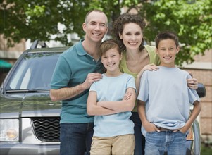 Family with two children in front of car.
