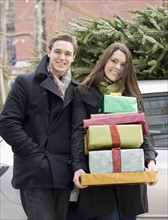 Couple holding stack of Christmas gifts. Date : 2008
