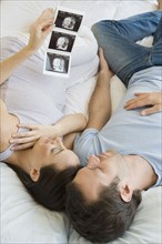 Pregnant Hispanic couple looking at ultrasound printout.