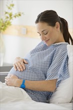Pregnant Hispanic woman with hands on belly.