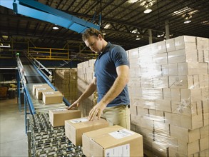 Warehouse worker checking packages on conveyor belt. Date : 2008