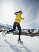 Woman and dog running in snow. Date : 2008