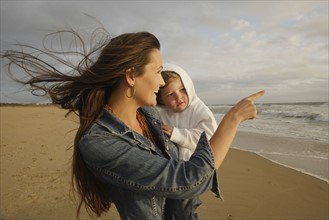 Mother holding baby at beach. Date : 2008