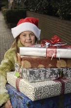 Girl holding stack of Christmas gifts. Date : 2008