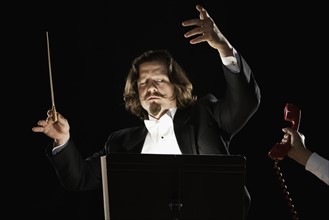 Telephone being handed to orchestral conductor. Date : 2008
