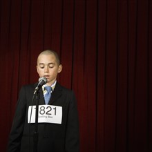 Boy wearing number and speaking on stage. Date : 2008