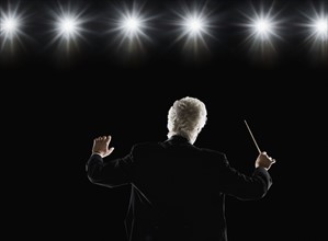 Man in tuxedo conducting under lights. Date : 2008