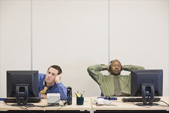 Multi-ethnic businessmen sitting at desks. Date : 2008